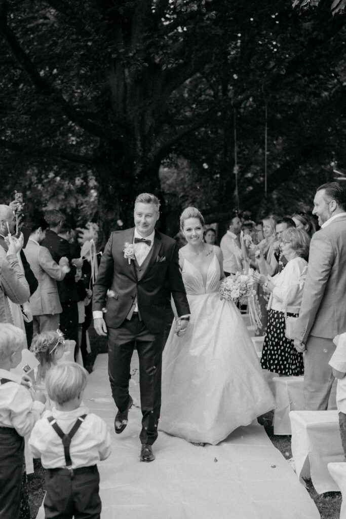 Hochzeitspaar spaziert durch Gäste im Freien