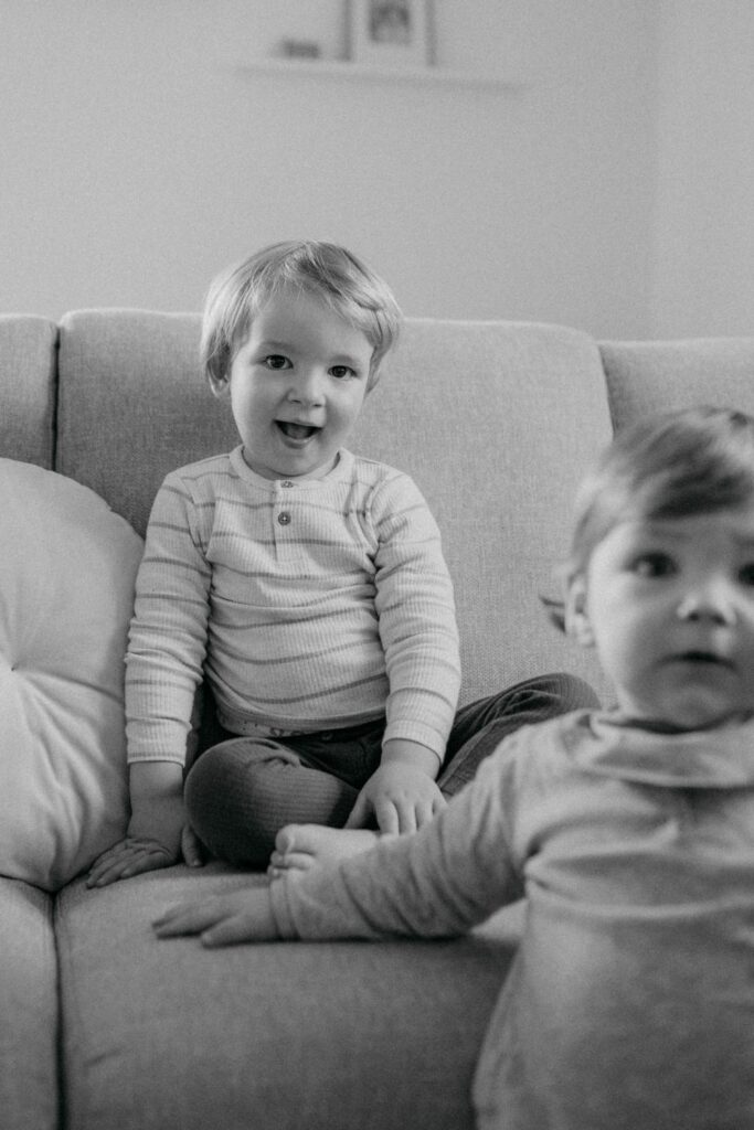 Zwei lächelnde Kleinkinder sitzen auf dem Sofa