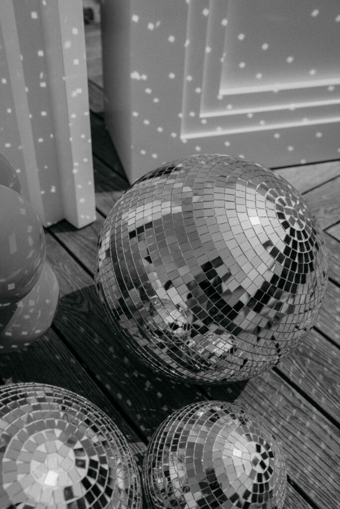 Schwarzweißfoto von reflektierenden Discokugeln auf Holzoberfläche