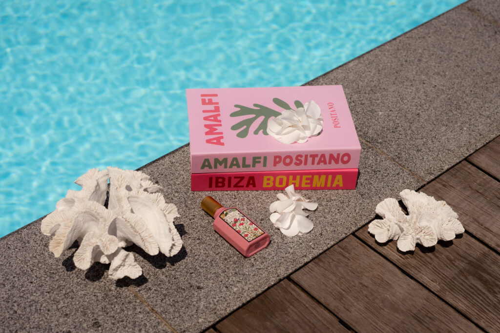 Bücher und Muscheln am Pool mit Parfüm
