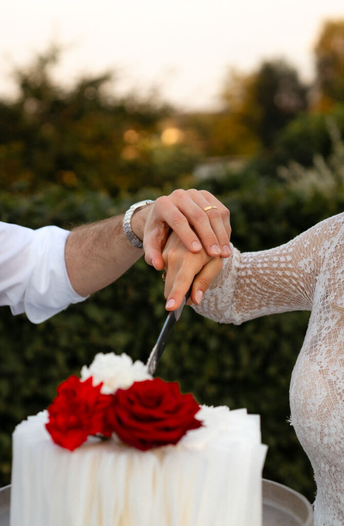 Hochzeitskuchen schneiden mit roten Rosen Dekoration