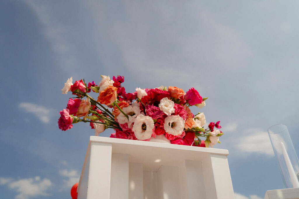 Bunte Blumendekoration auf weißem Tisch im Freien