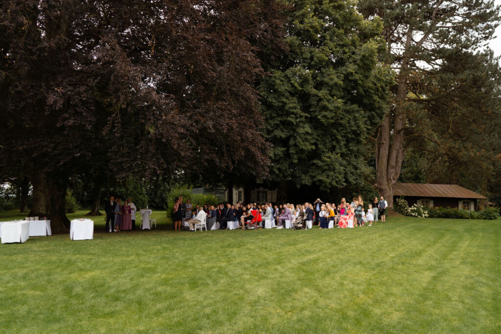 Gartenhochzeit mit Gästen unter großen Bäumen feiern