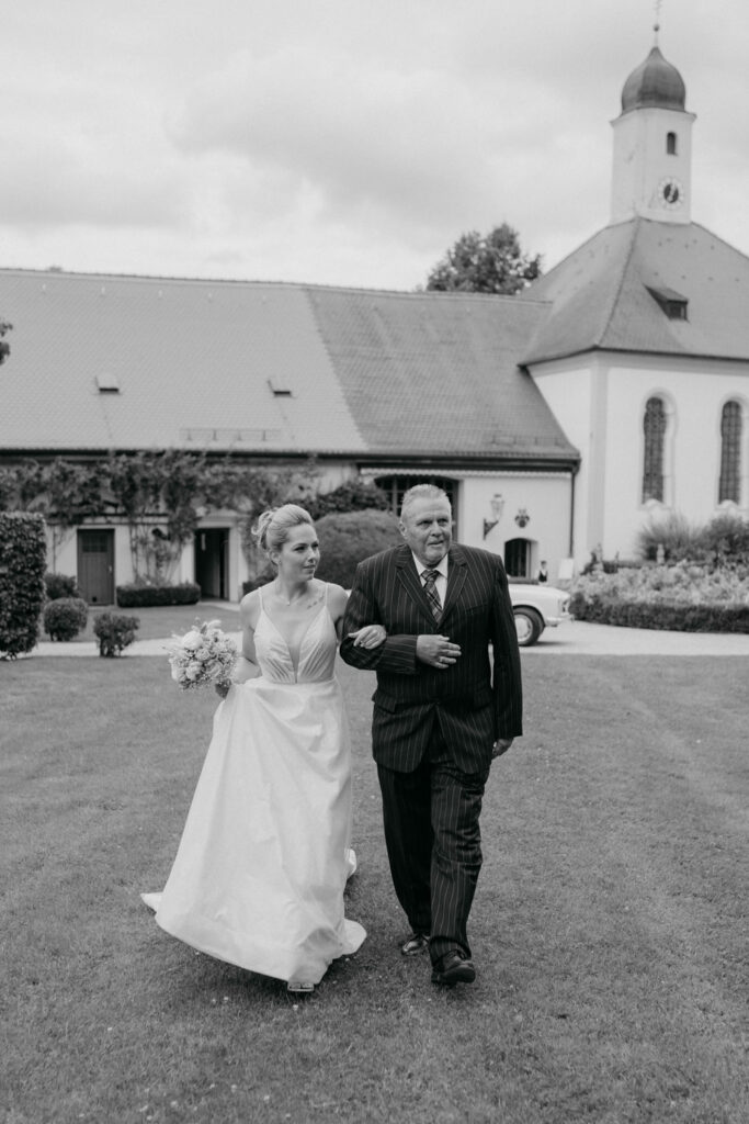 Braut und Begleiter vor einer Kirche spazierend