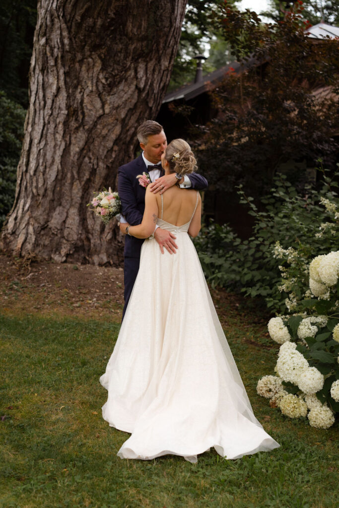 Brautpaar umarmt sich im Garten bei Hochzeit