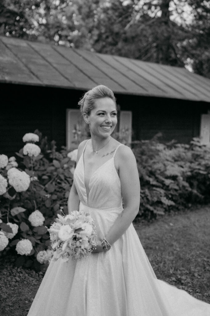 Braut in weißem Kleid mit Blumenstrauß draußen