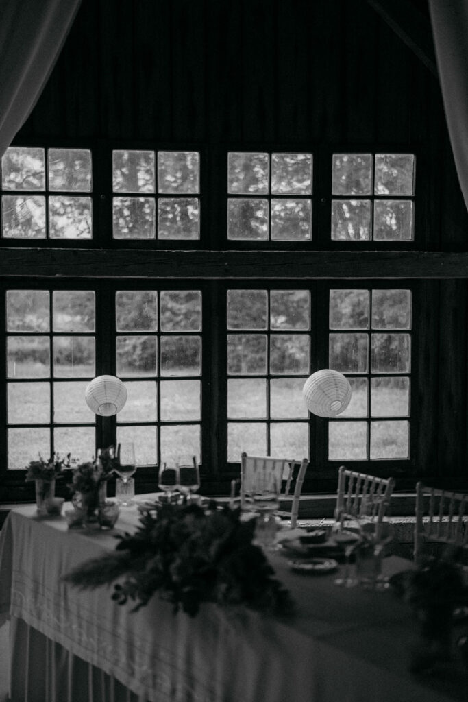 Eleganter Hochzeitstisch vor großen Fenstern im Freien