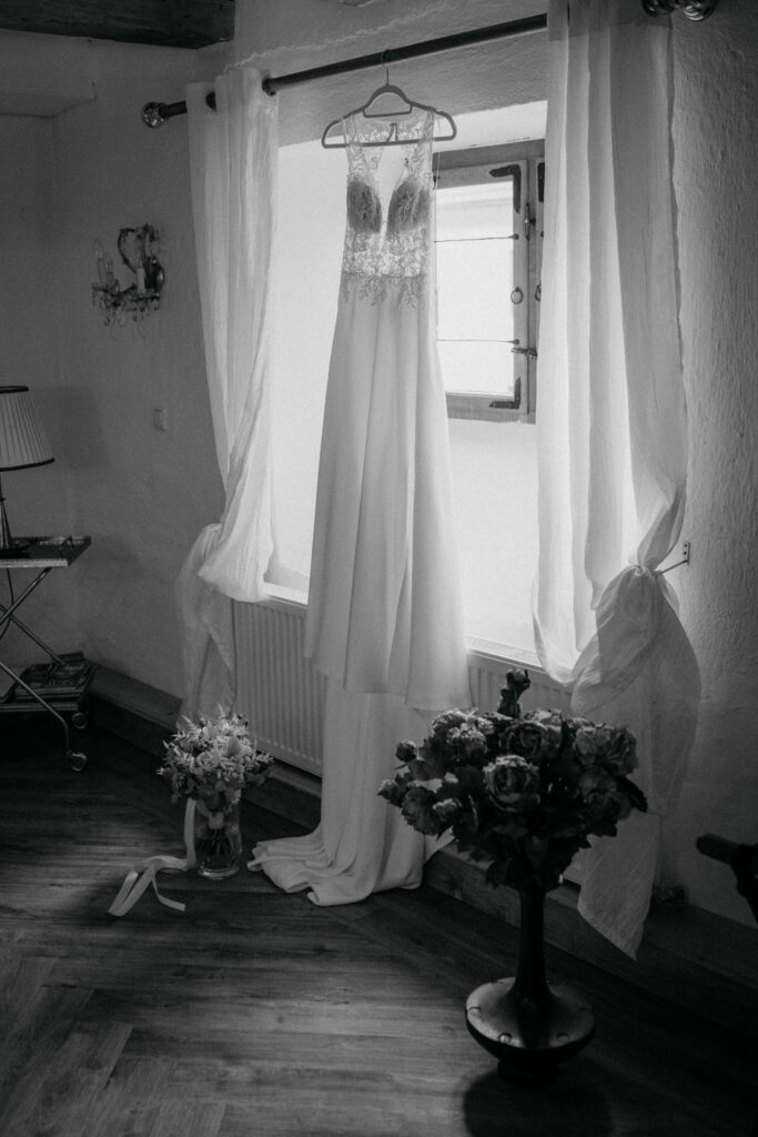 Elegantes Hochzeitskleid hängt neben Fenstervorhängen