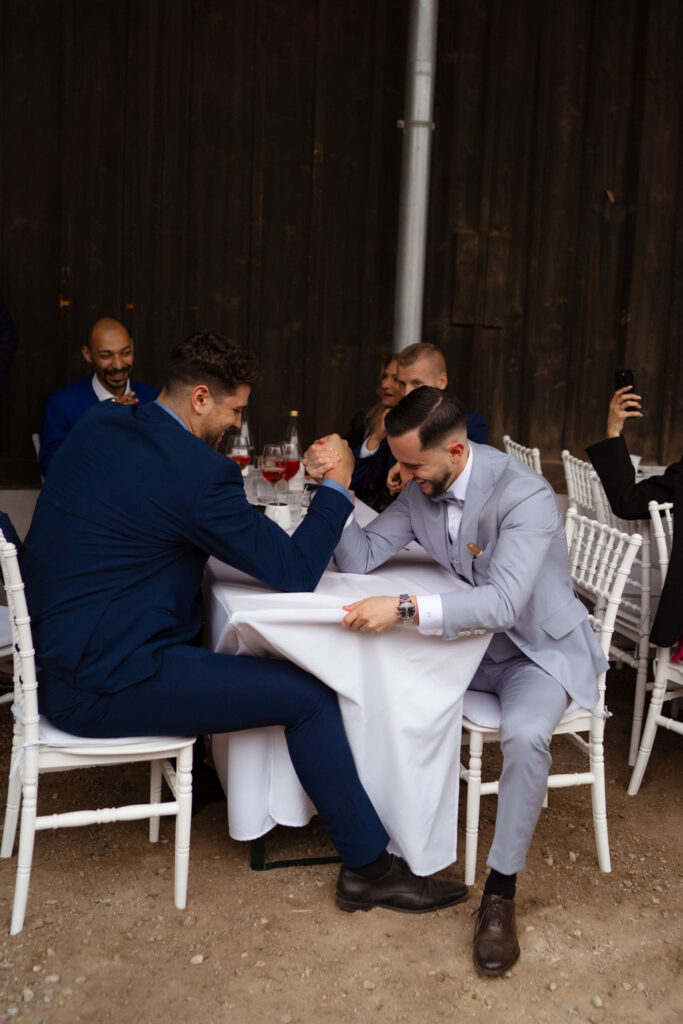 Zwei Männer machen Armdrücken auf Hochzeitstisch.