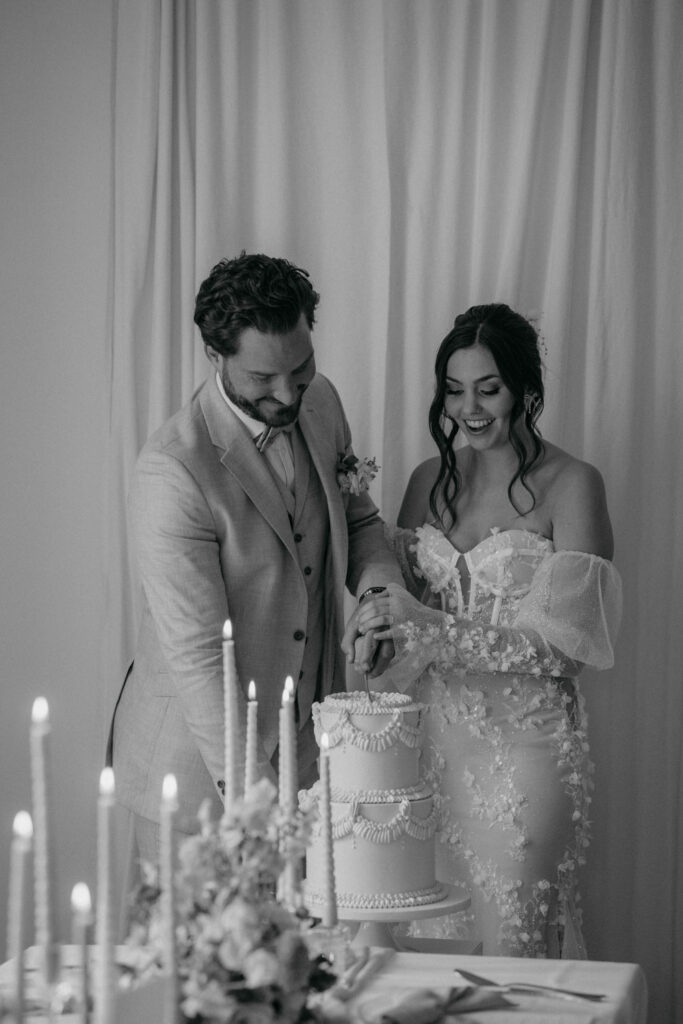 Brautpaar schneidet Hochzeitstorte bei Feier an