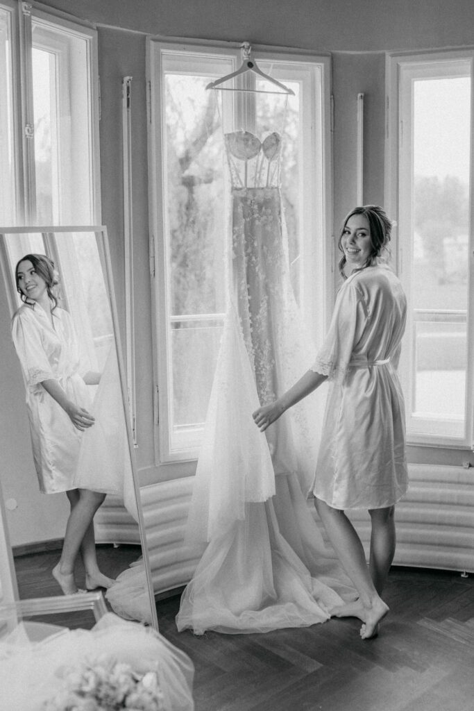 Braut betrachtet ihr Hochzeitskleid im Spiegel