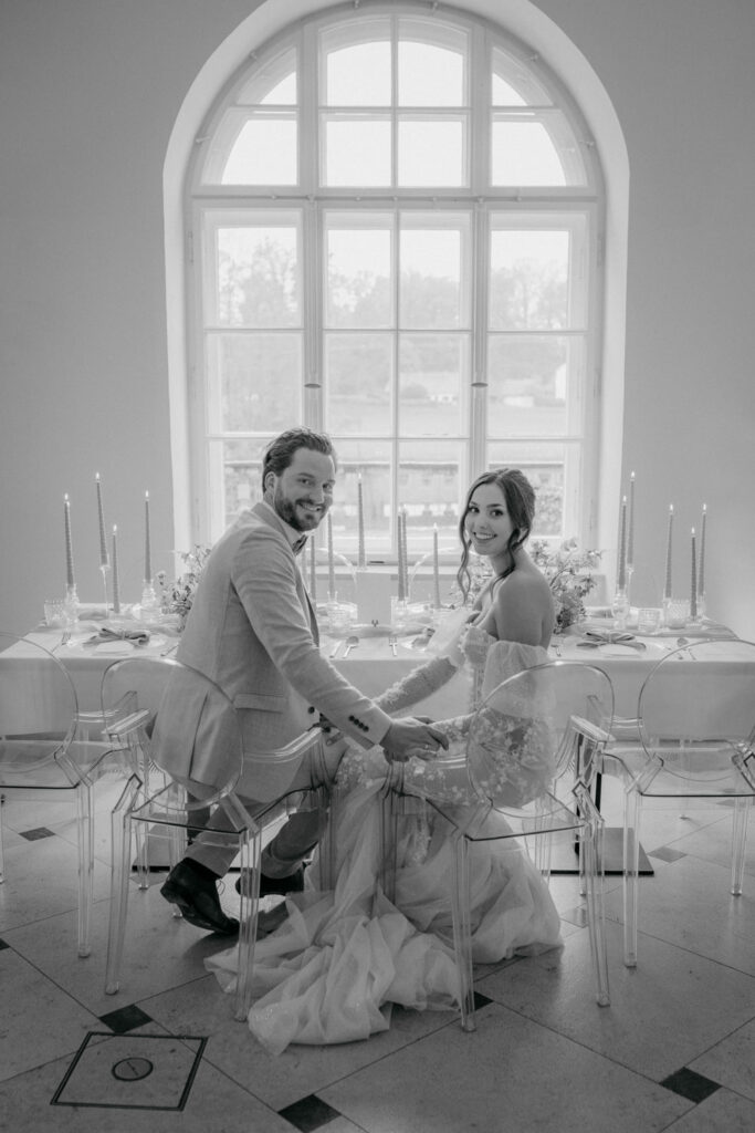 Hochzeitspaar sitzt an elegant dekoriertem Tisch.