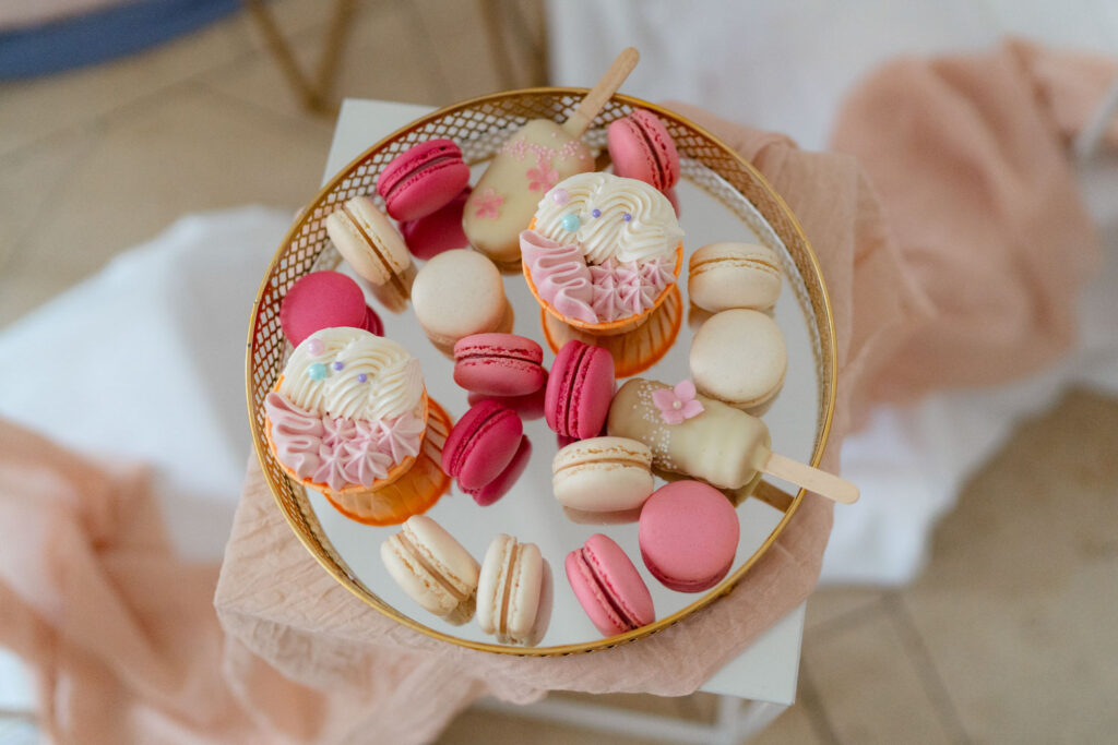 Bunte Macarons und Cupcakes auf goldenem Tablett