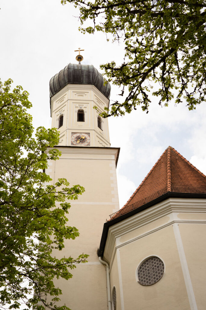 Kirchturm mit grünen Bäumen und Himmelblick