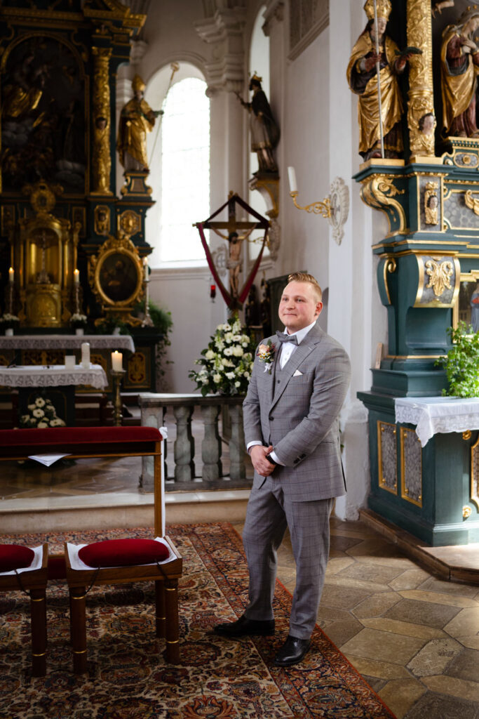Bräutigam in grauem Anzug in historischer Kirche