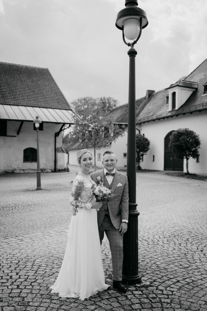 Hochzeitspaar posiert in einem gepflasterten Hof.