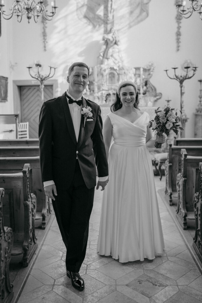 Hochzeitspaar schreitet den Kirchgang entlang lächelnd