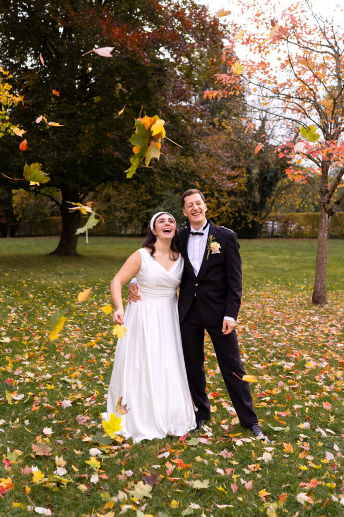 Fröhliches Brautpaar im herbstlichen Garten feiern Hochzeit